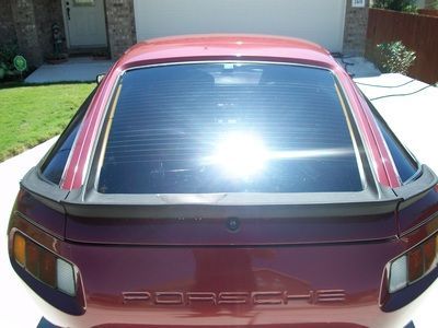 A red porsche is parked in front of a house
