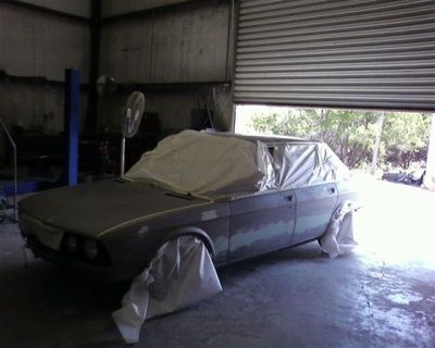 A car is covered in plastic in a garage
