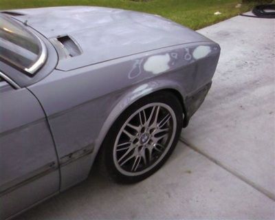 A gray car is parked on the side of the road