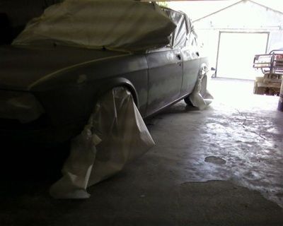 A car is covered in plastic in a garage