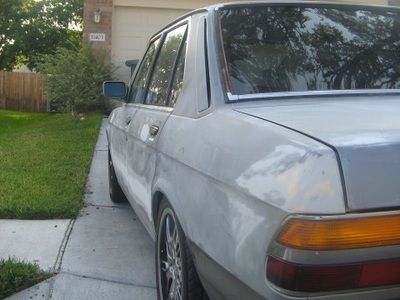 A silver car is parked on a sidewalk in front of a house