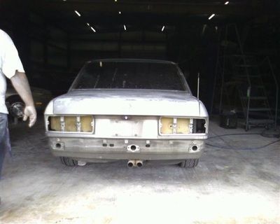 A man standing next to a silver car in a garage