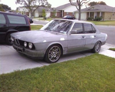 A gray car is parked on the side of the road