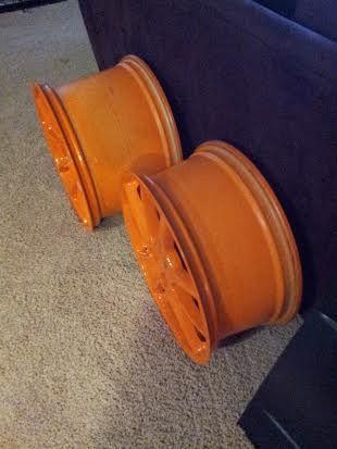 Two orange wheels are sitting on the floor next to a couch