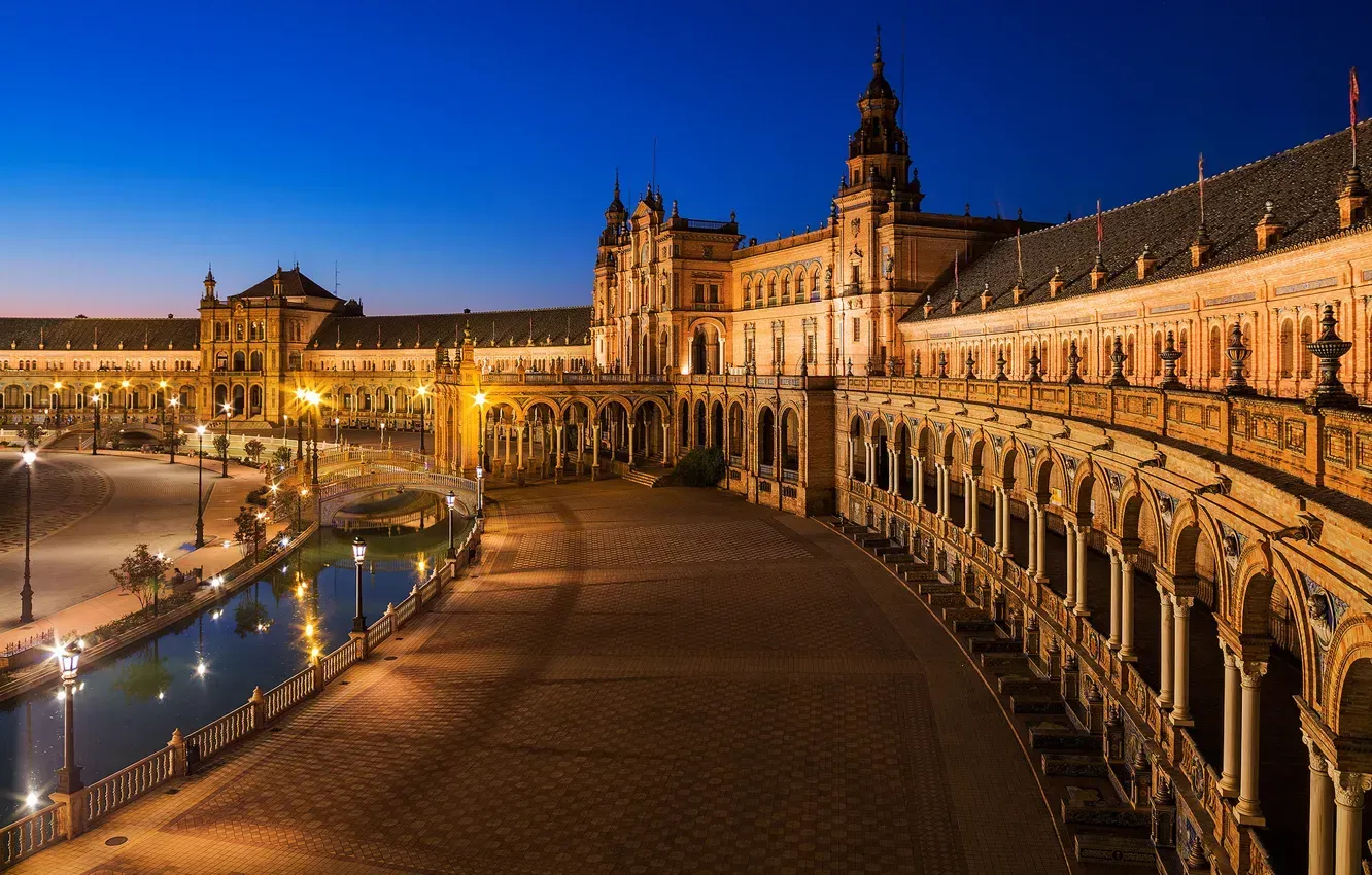 A large building with arches and columns is lit up at night.