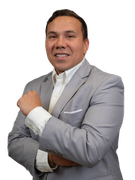 Man in gray blazer and white shirt, smiling with crossed arms.