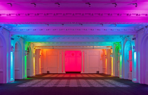A large room with a rainbow of lights on the ceiling.