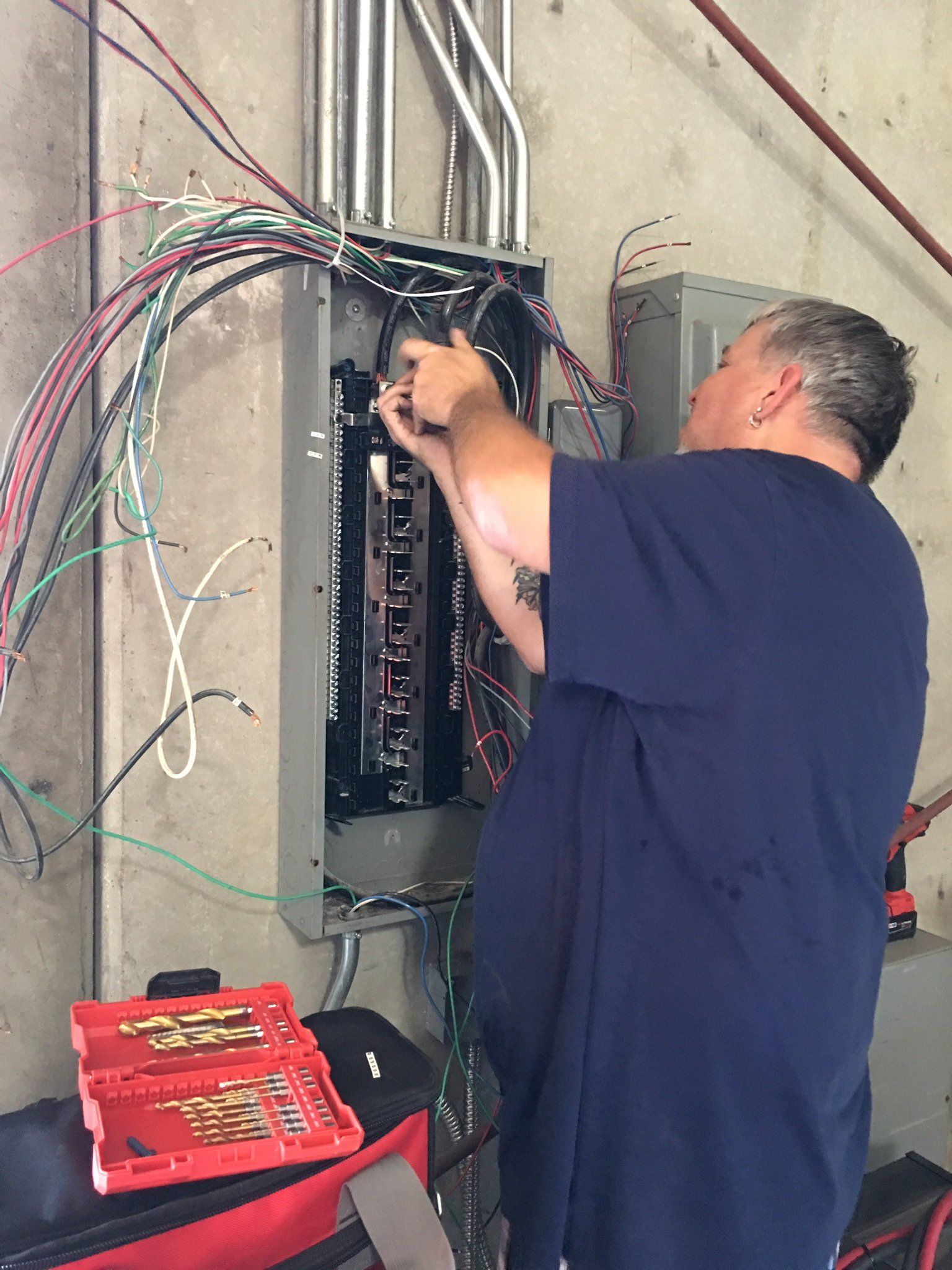 A man in a blue shirt is working on an electrical box