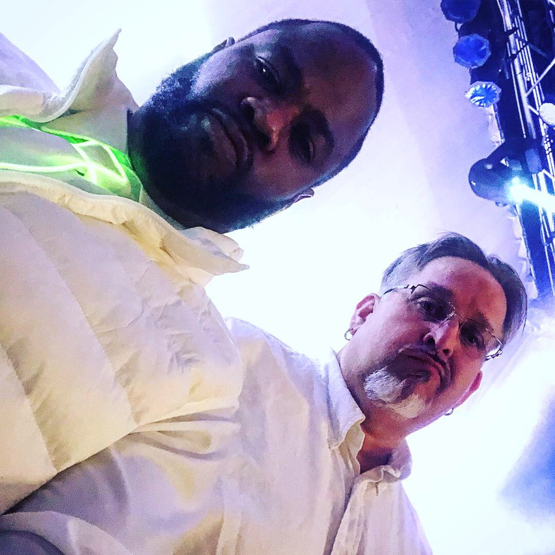 Two men are posing for a picture in front of a stage.