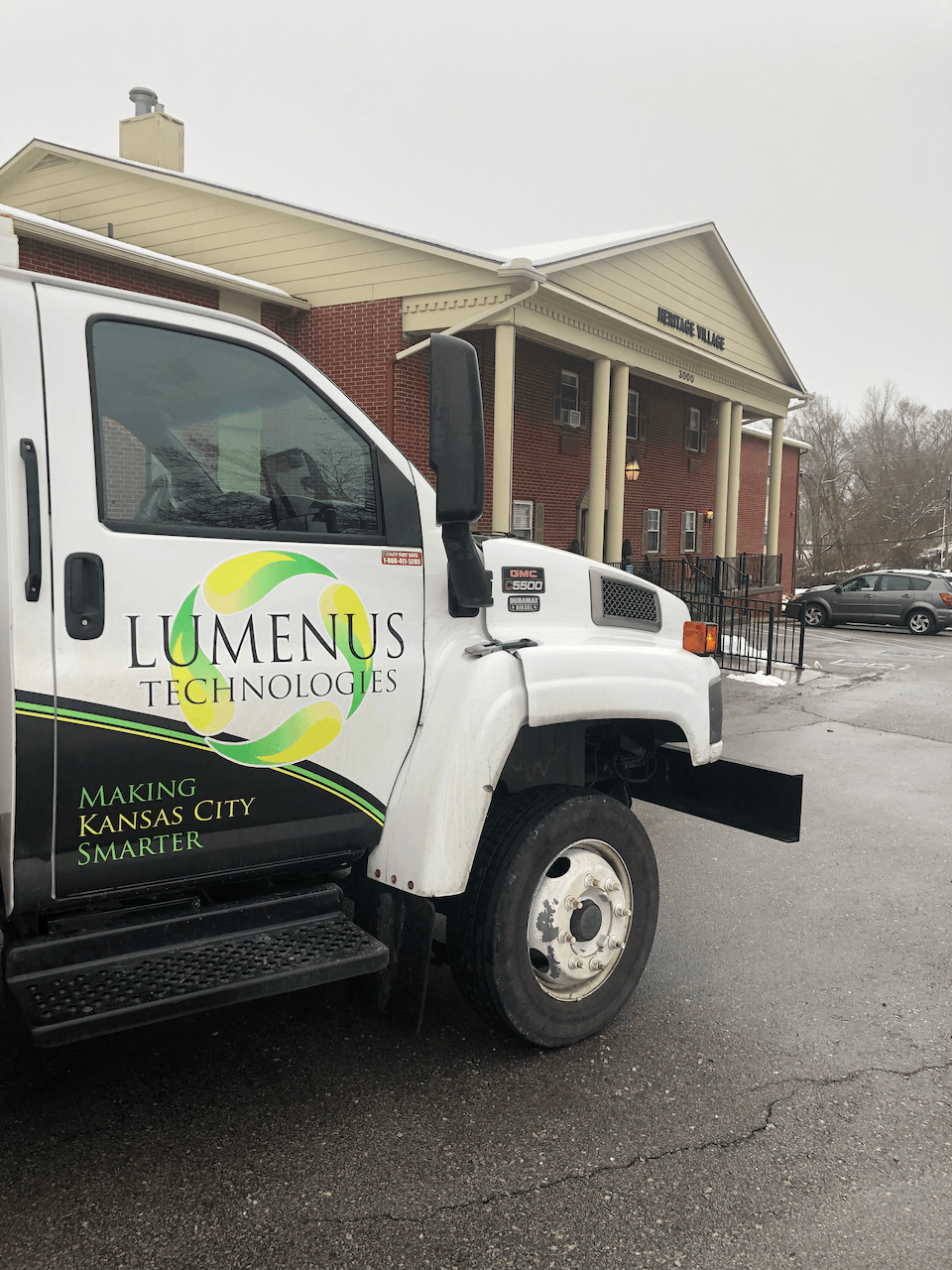 A luminus truck is parked in front of a building