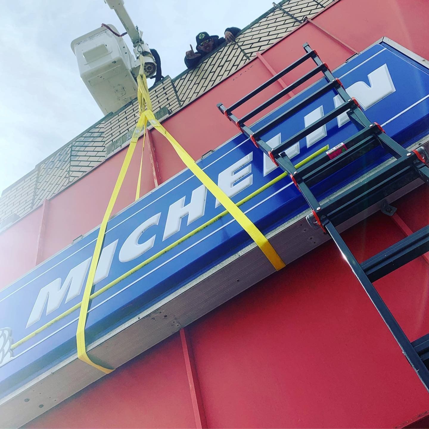 A michelin sign is being lifted by a ladder