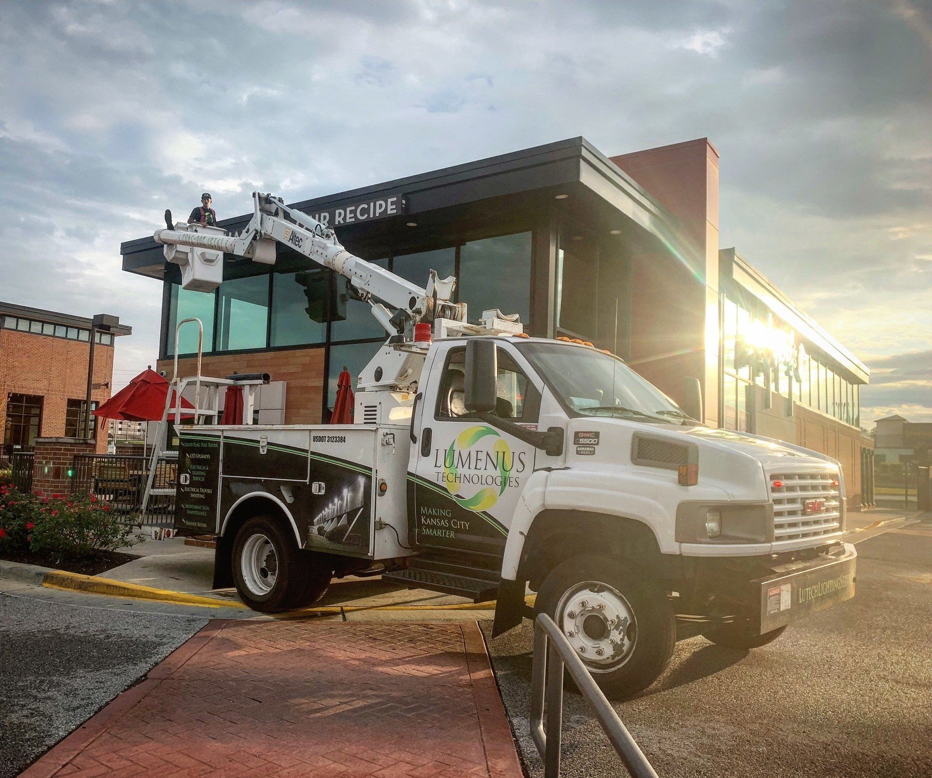 A white truck with a crane on the back is parked in front of a building.