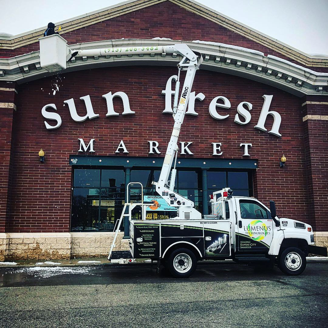 A truck is parked in front of a sun fresh market sign.