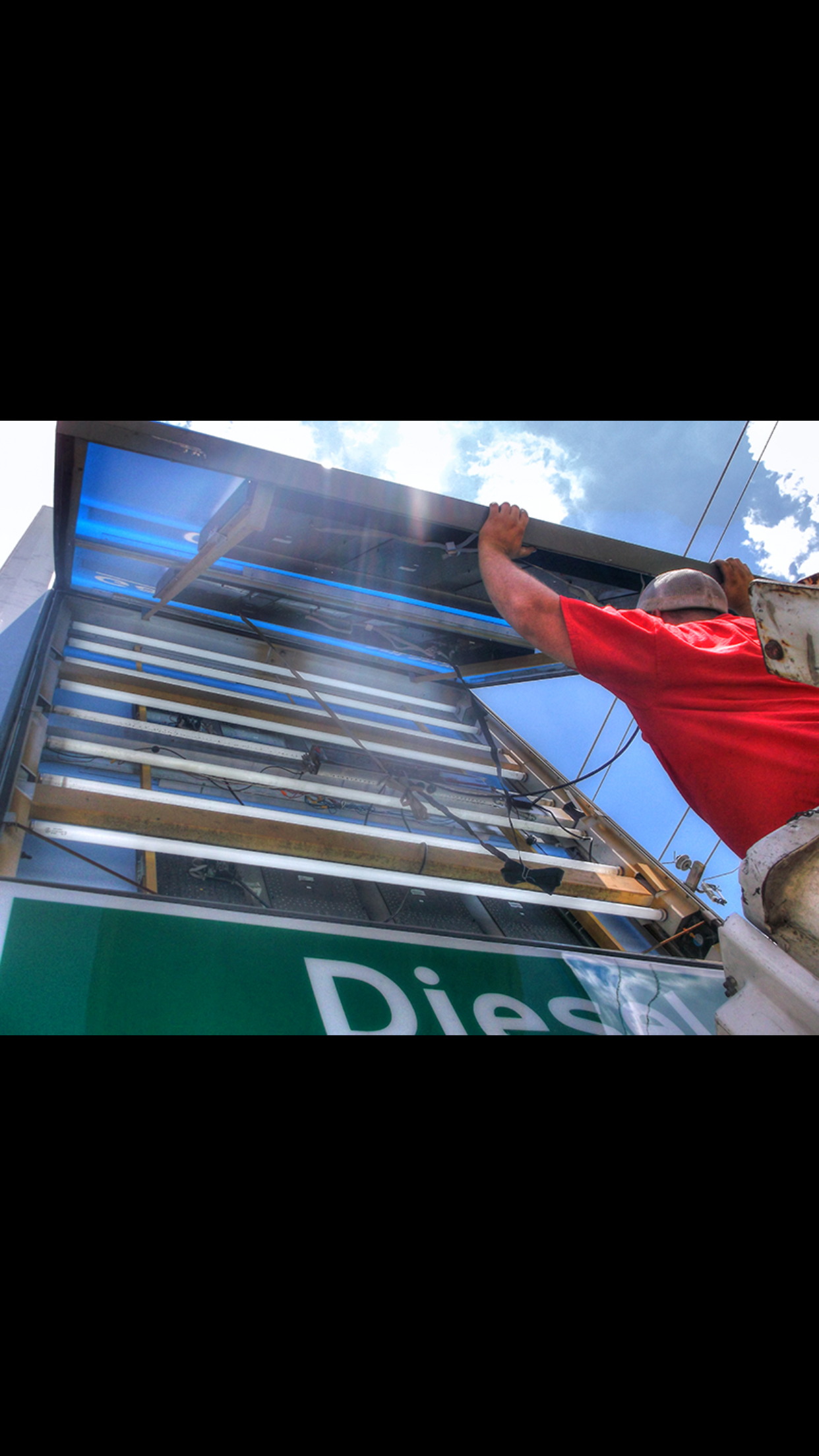A man in a red shirt is standing in front of a sign that says diesel.