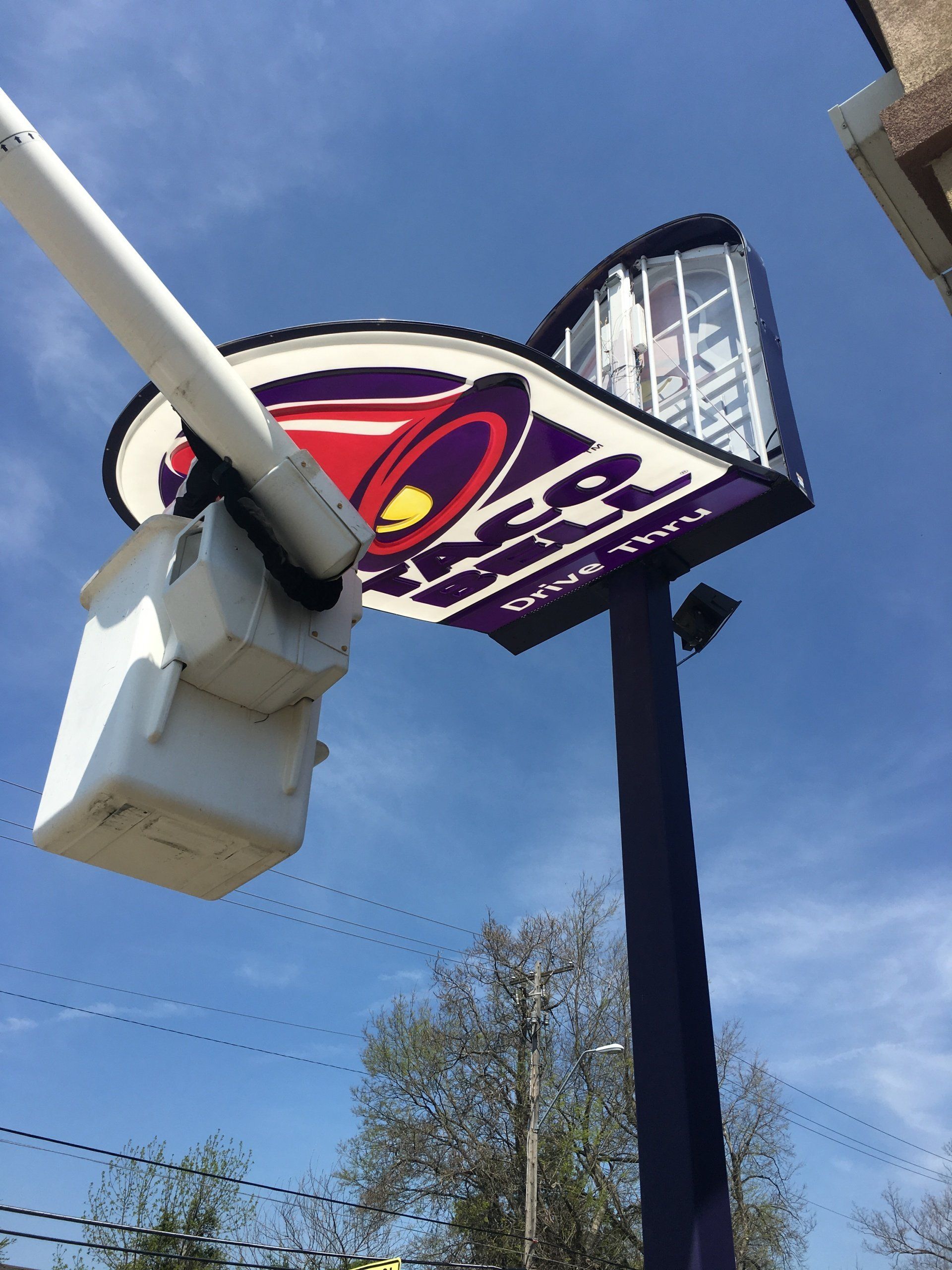 A taco bell sign is being installed on a pole