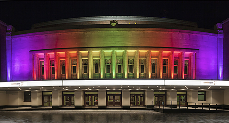 A large building with rainbow lights on it at night