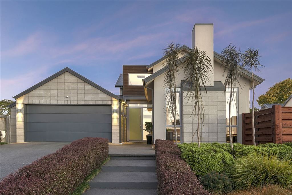 Modern house exterior with garage, front walkway, and landscaped yard at dusk