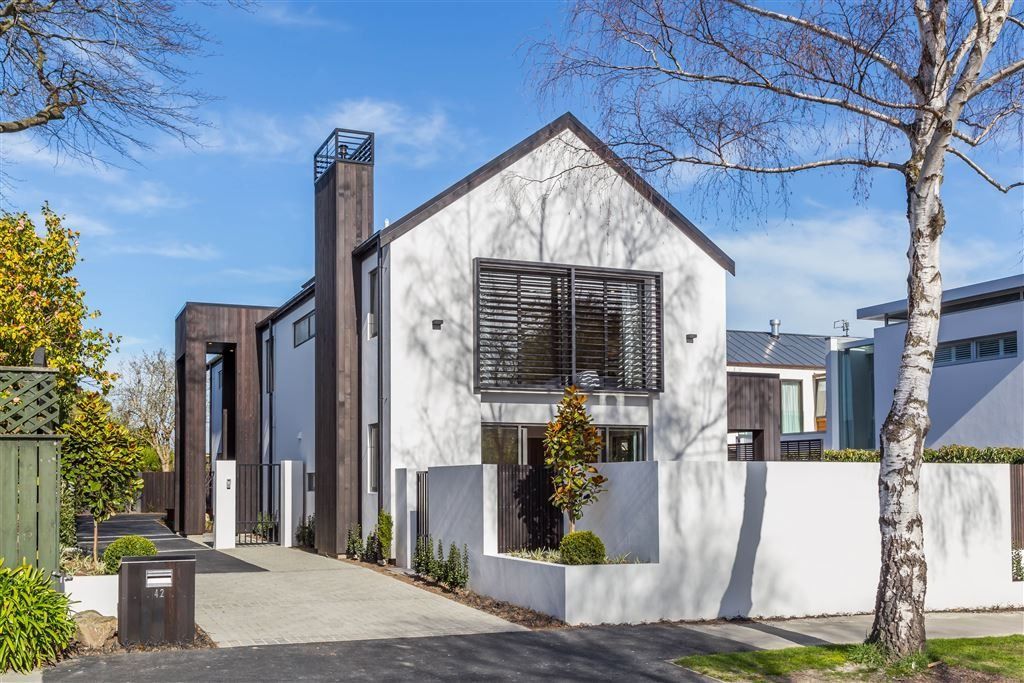 Modern white house with dark trim, large windows, and a front yard on a sunny day
