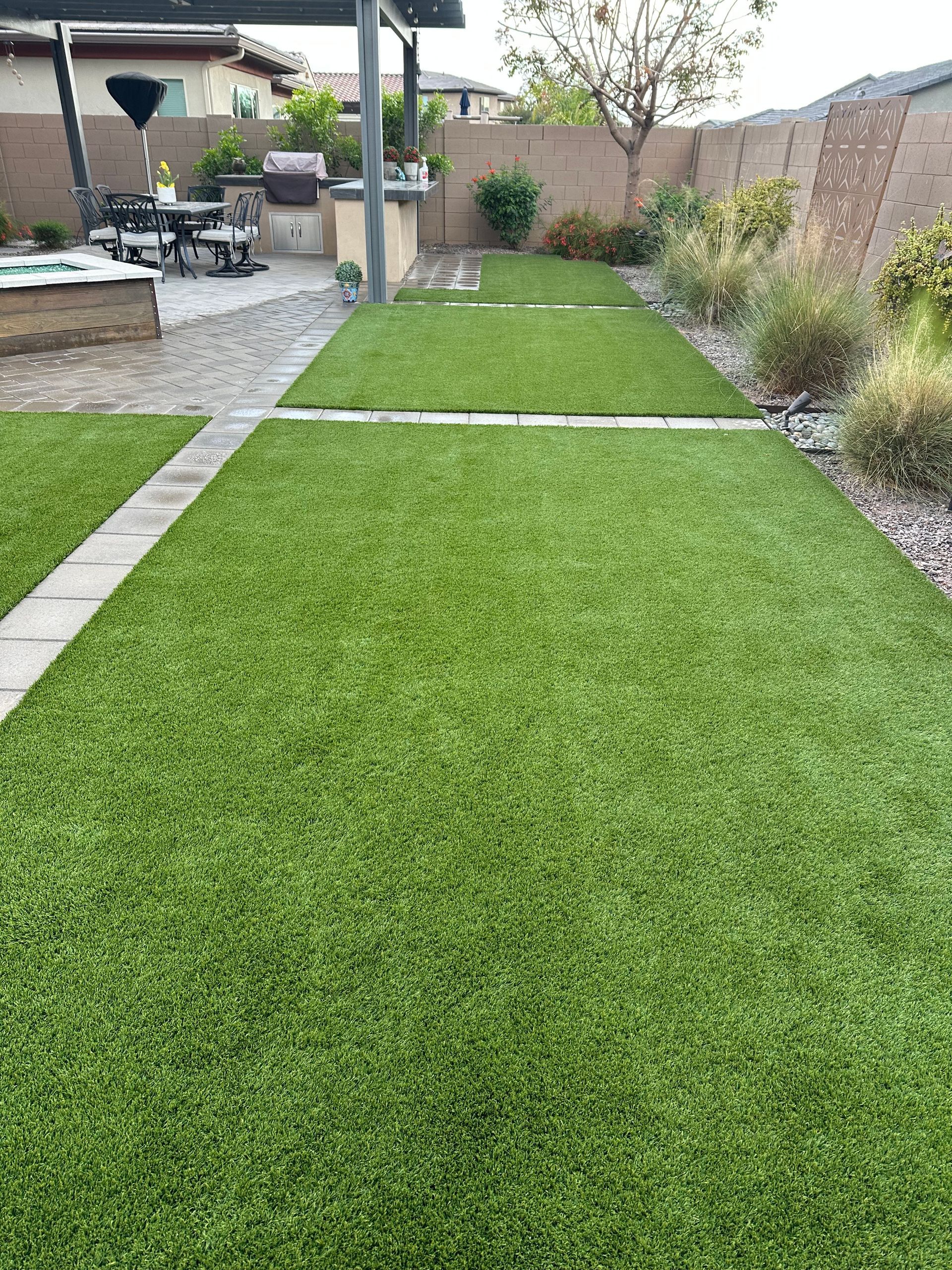 A backyard with a lush green lawn and a walkway.