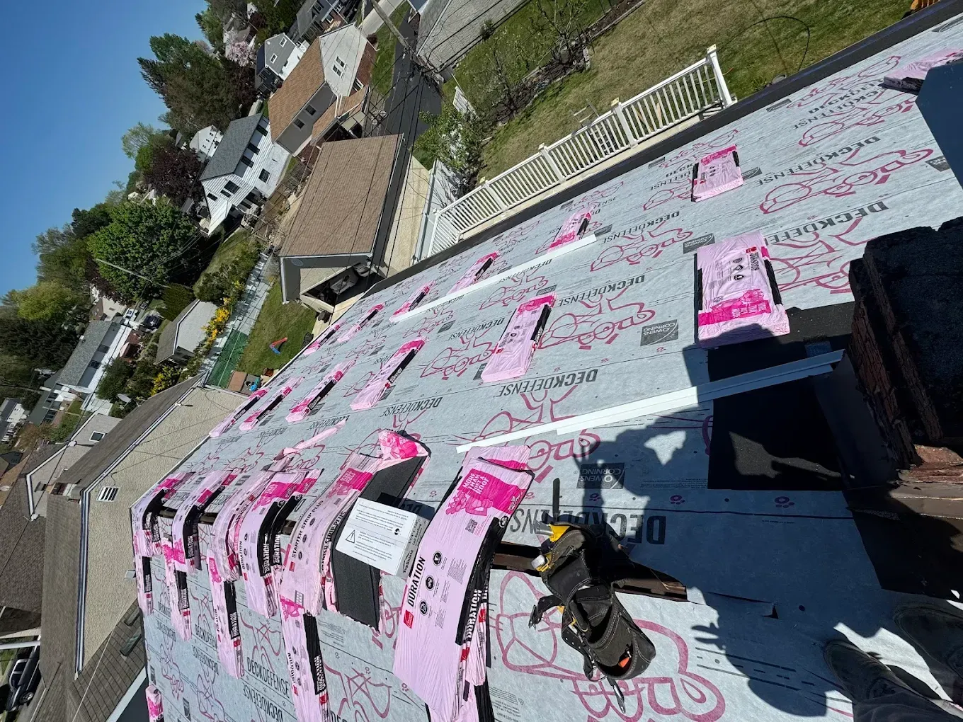 Roof covered in pink-and-white handwritten signs and a small black bag beside a roadside fence