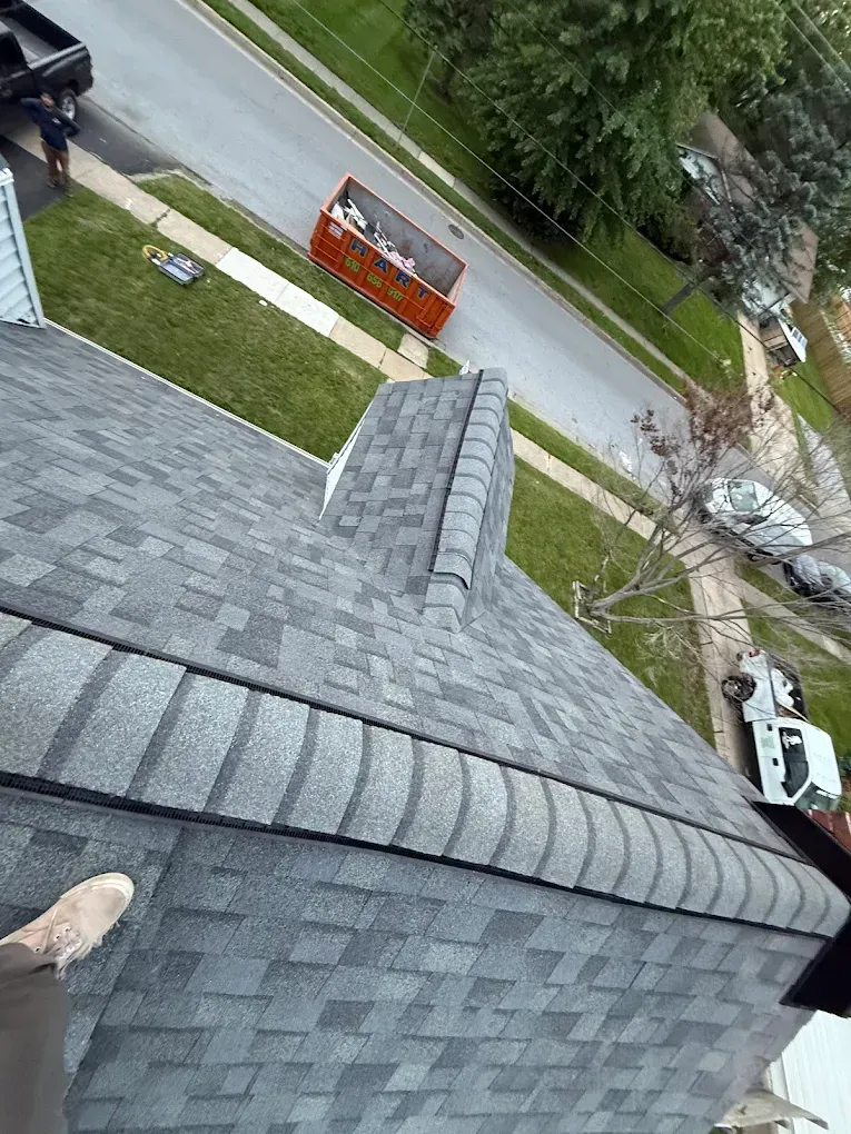 Roof view of a street with an orange barricade, trees, and two parked vehicles below