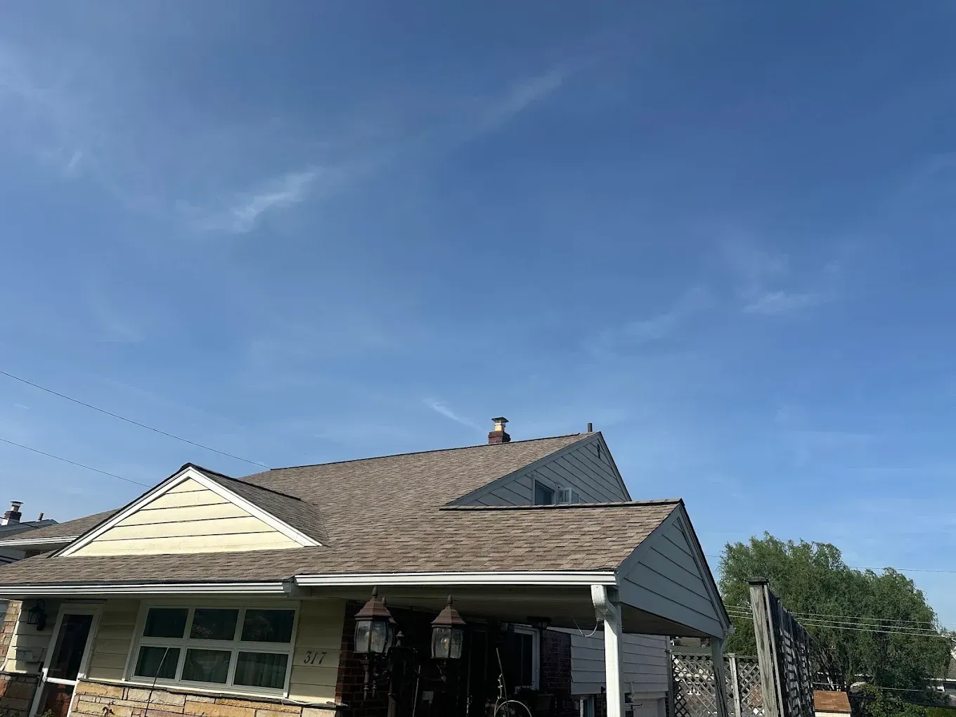 House roof and front porch under a bright blue sky