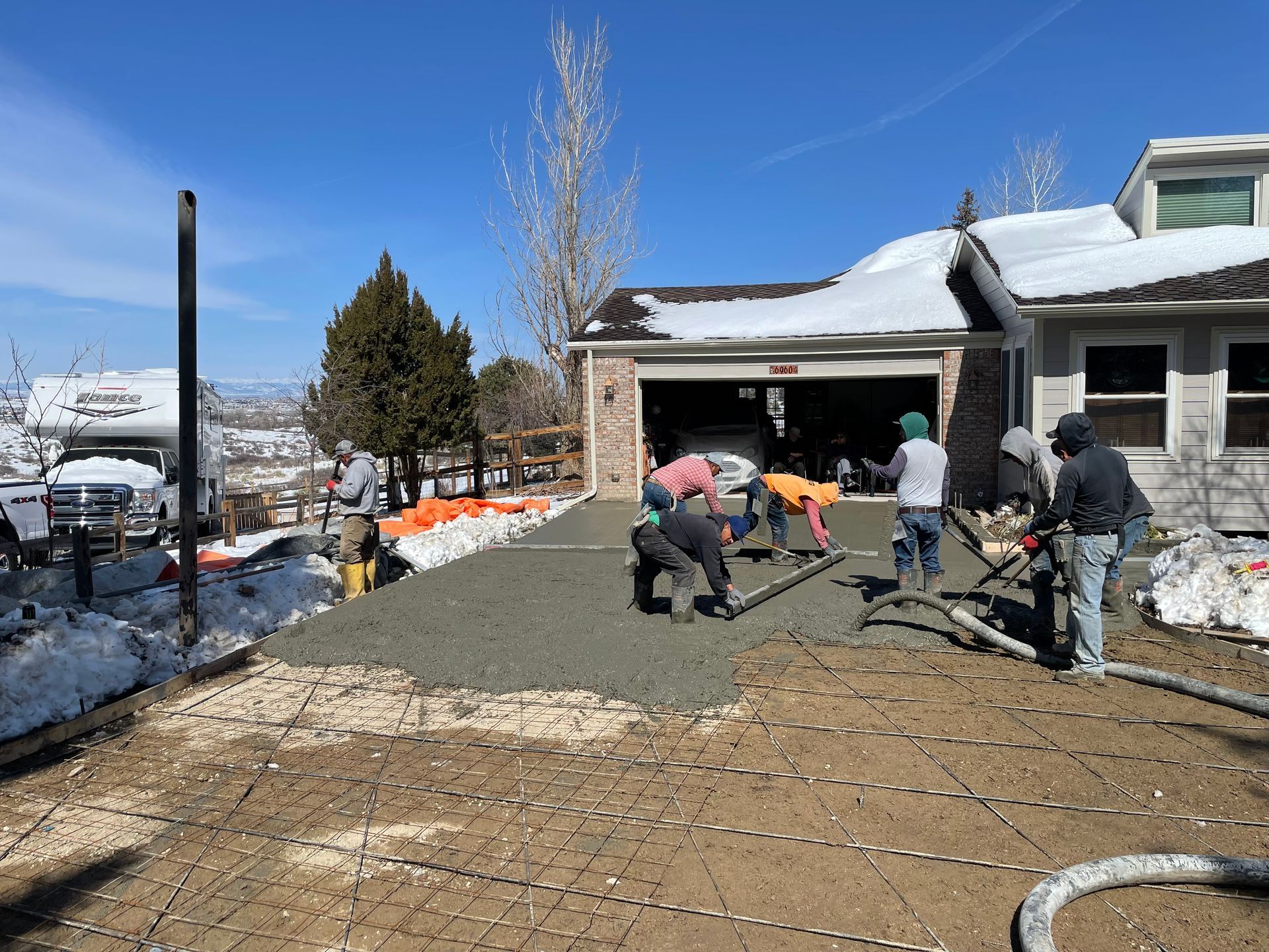 A group of people are working on a driveway in front of a house.