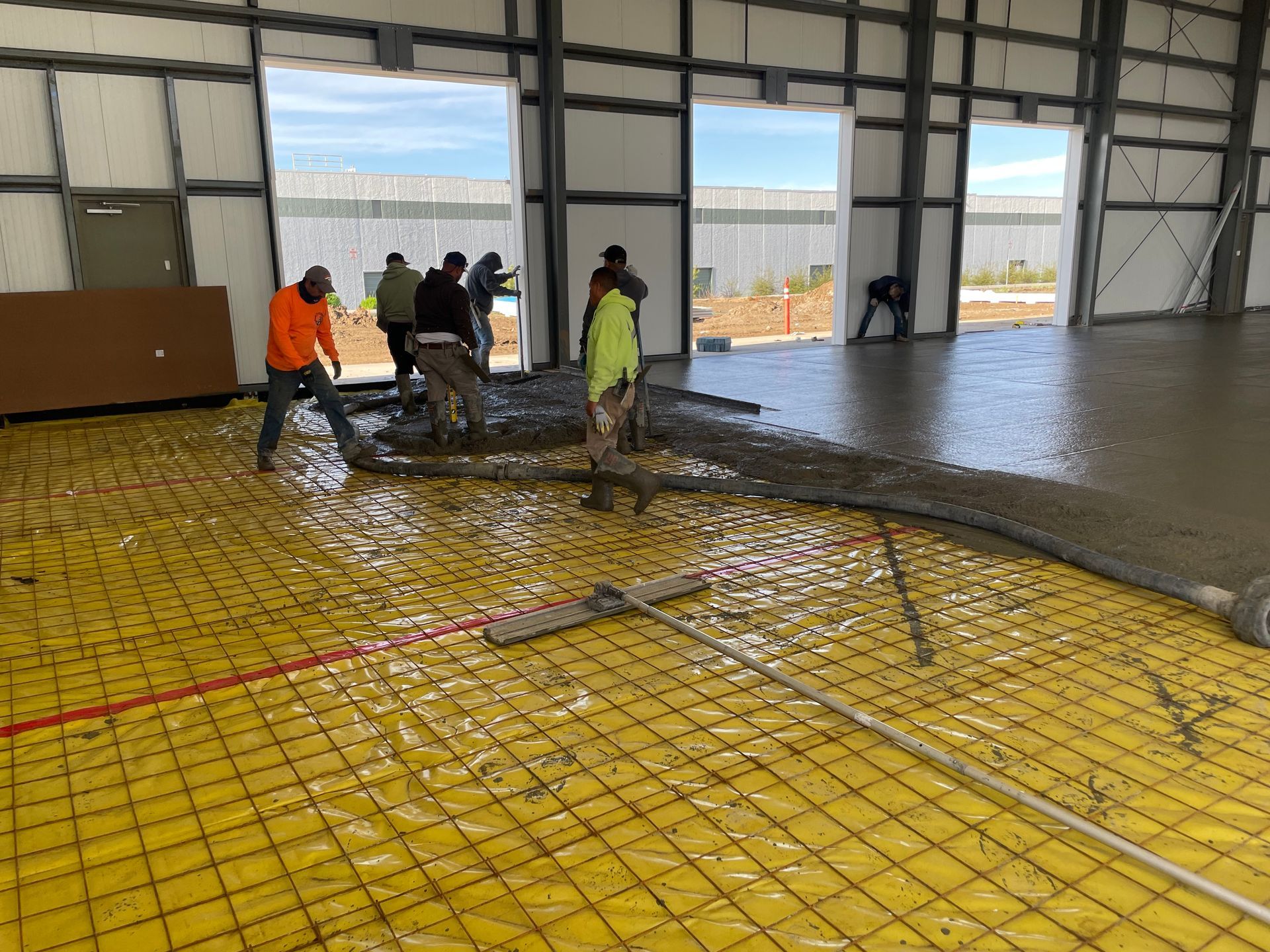 A group of construction workers are working on a concrete floor.