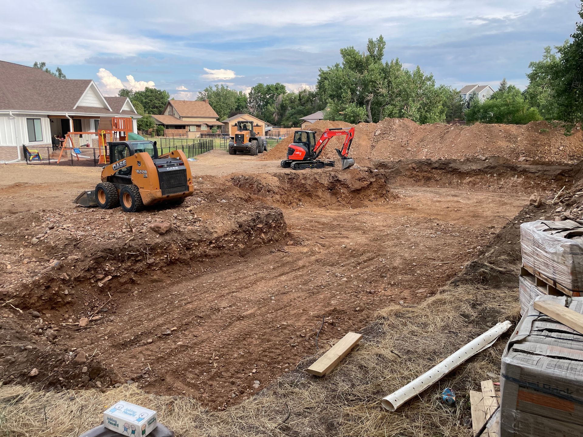 A construction site with a lot of dirt and a house in the background.