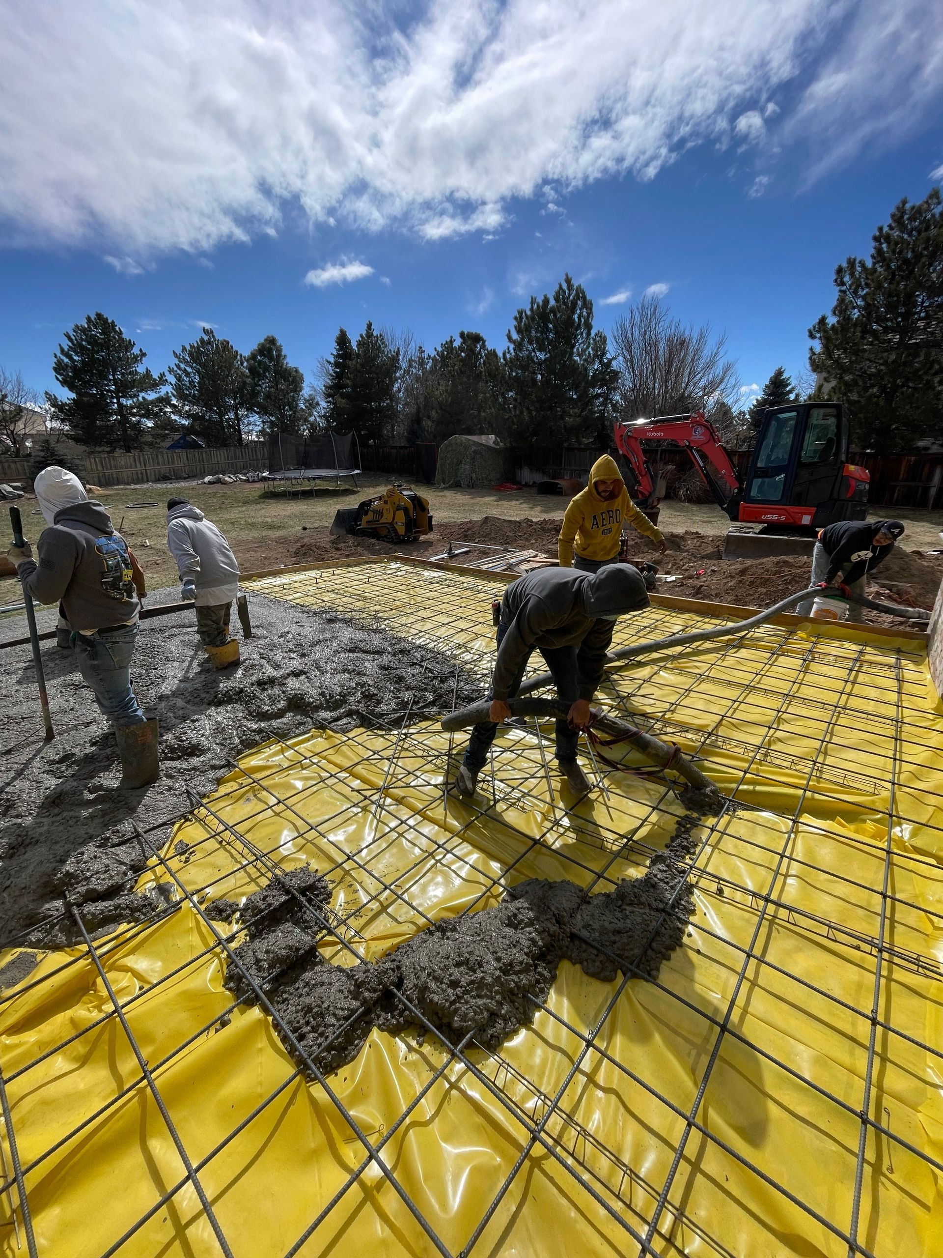 A group of construction workers are working on a concrete floor.