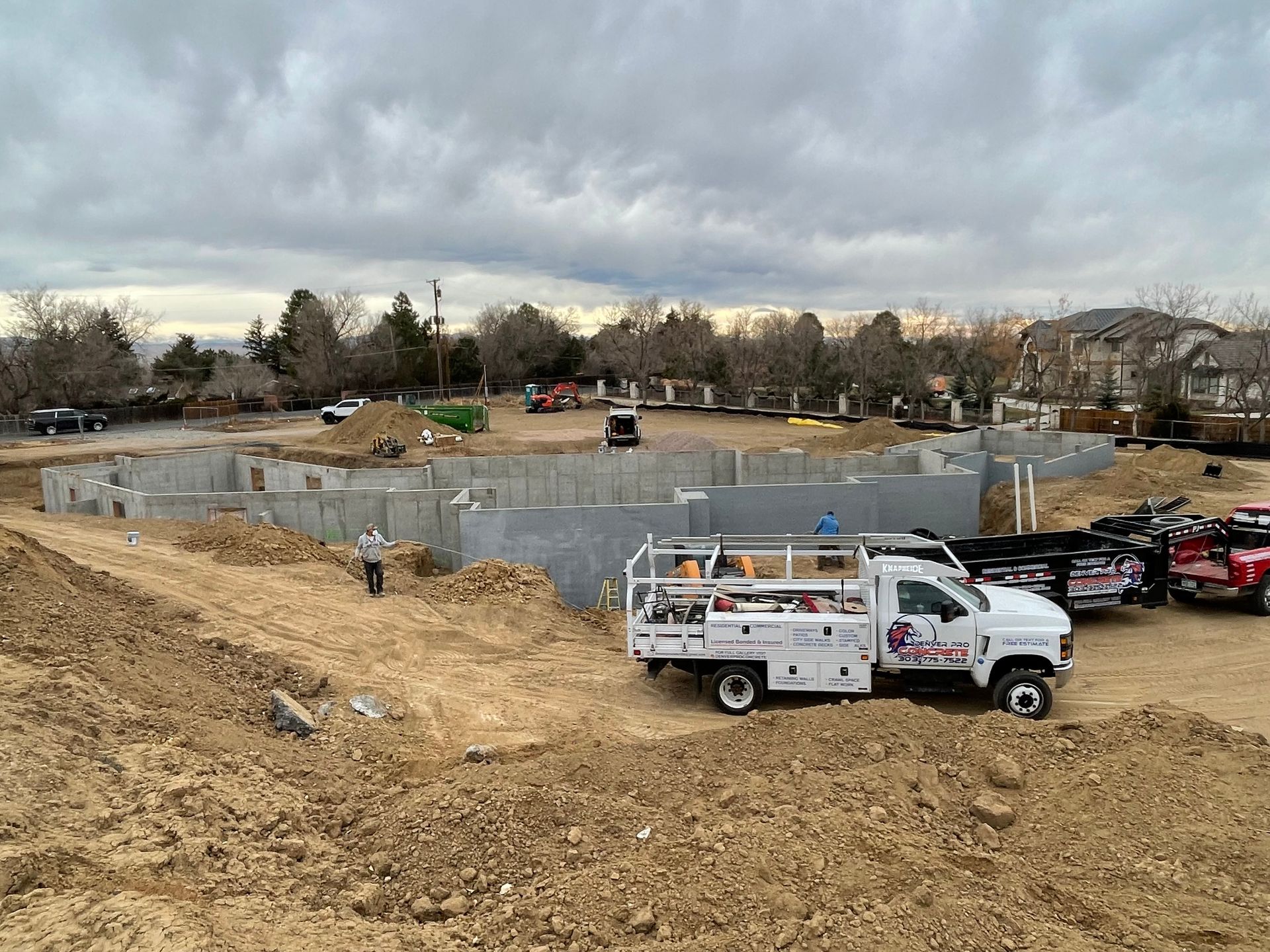 A white truck is parked in the dirt in front of a construction site.