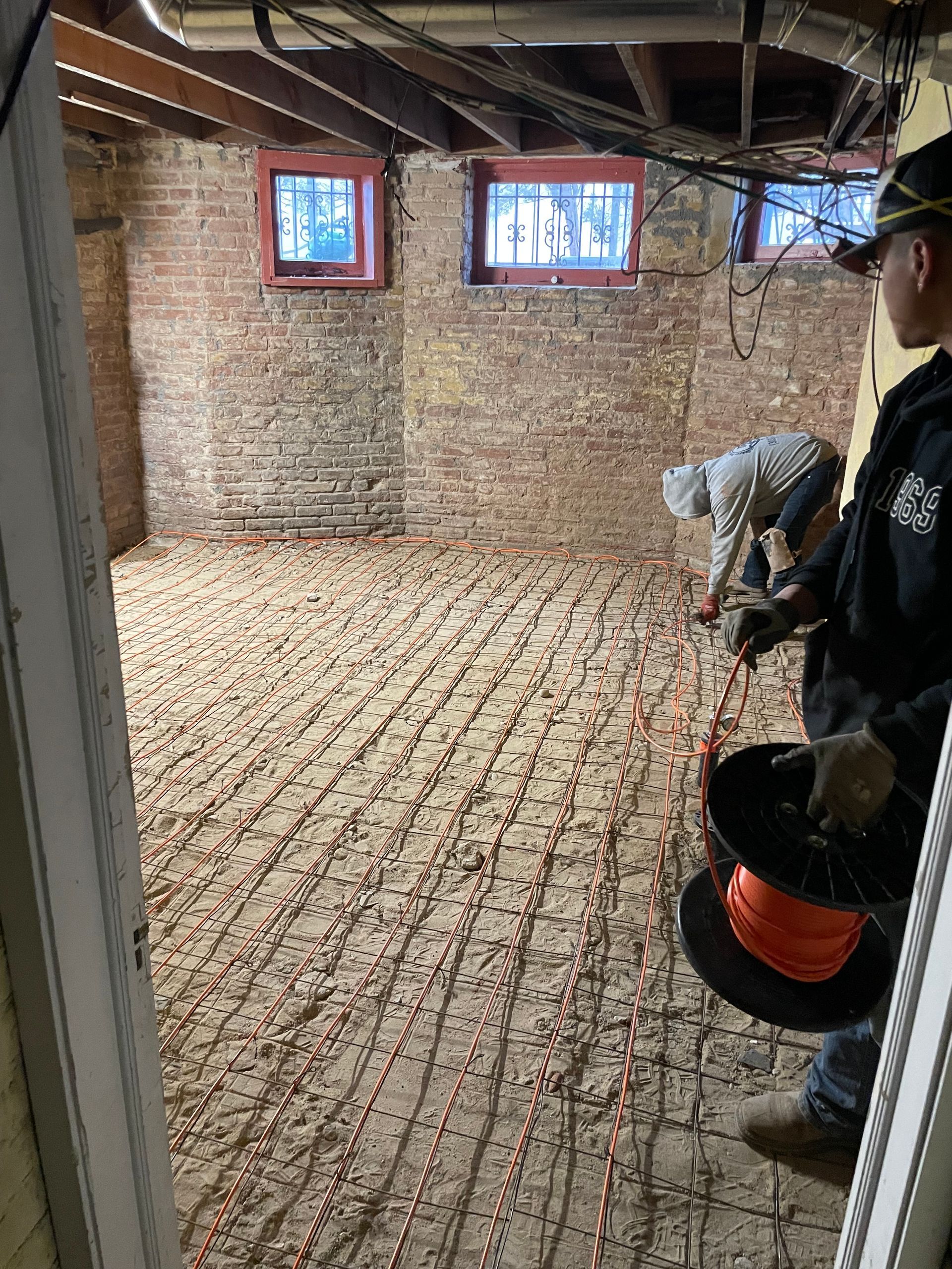 A man is working on the floor of a basement.