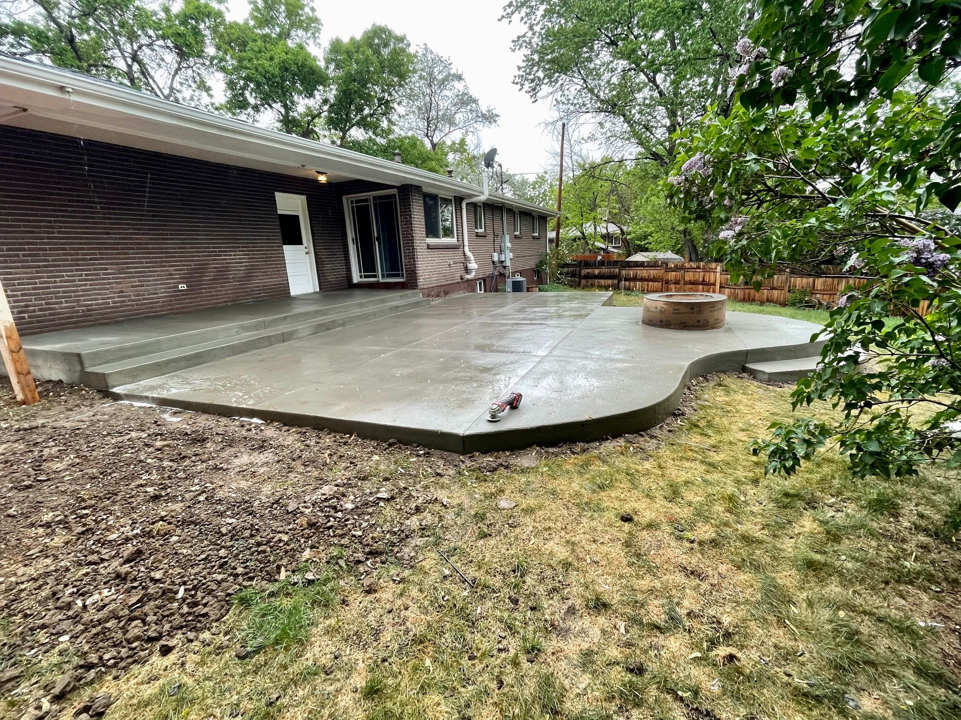 A concrete patio is being built in the backyard of a house.