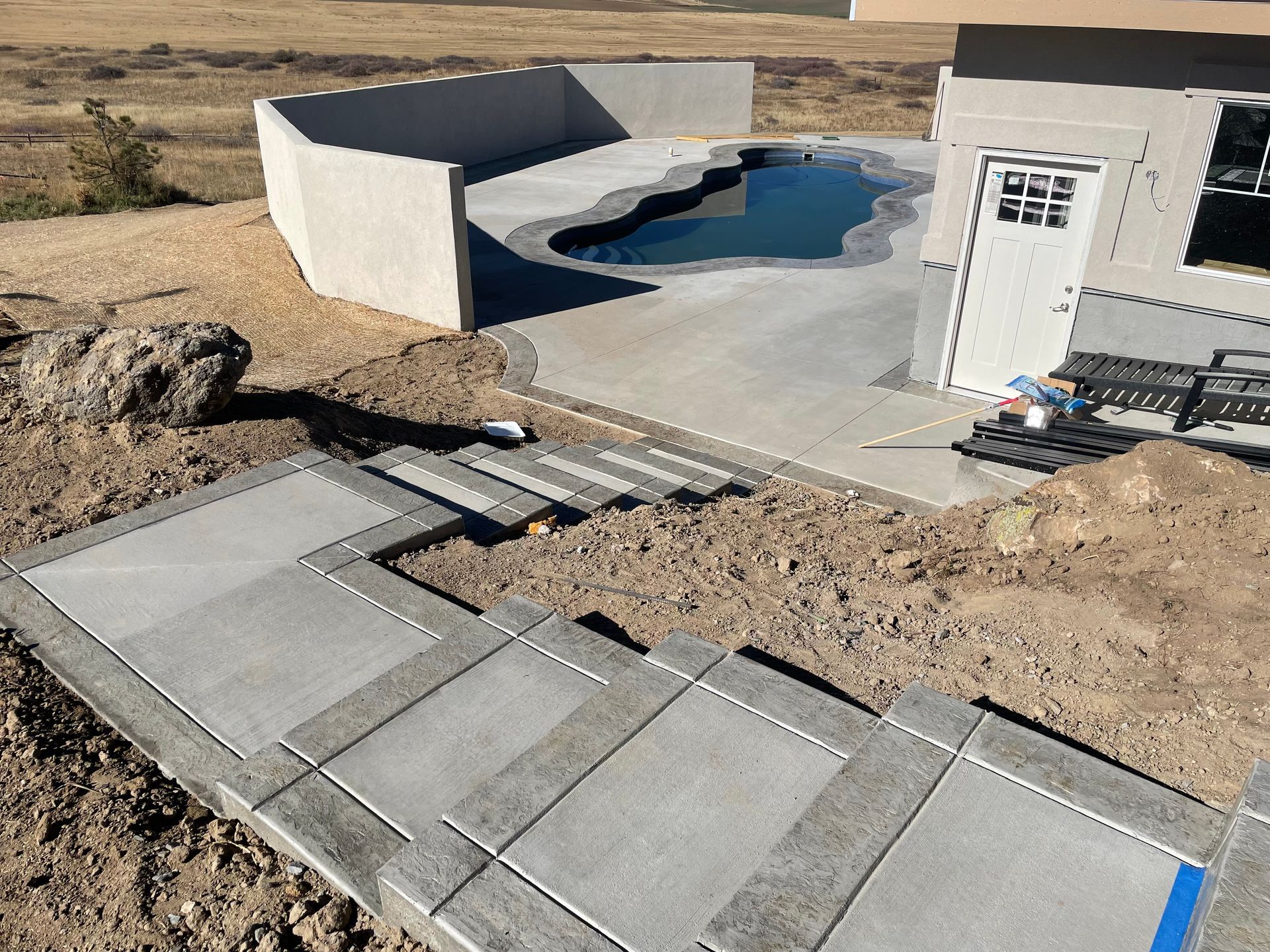 A concrete walkway is being built next to a swimming pool.