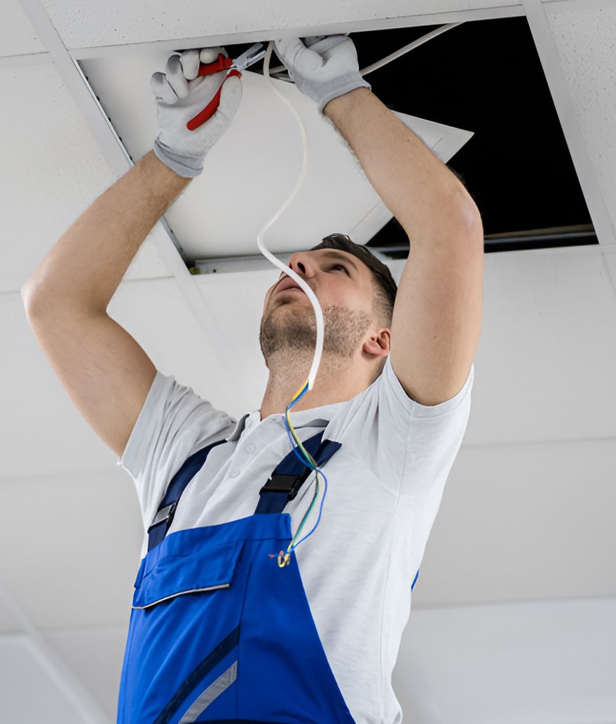 A Man Is Fixing A Light Fixture On The Ceiling — Steve Mason Electrical In Port Macquarie, NSW