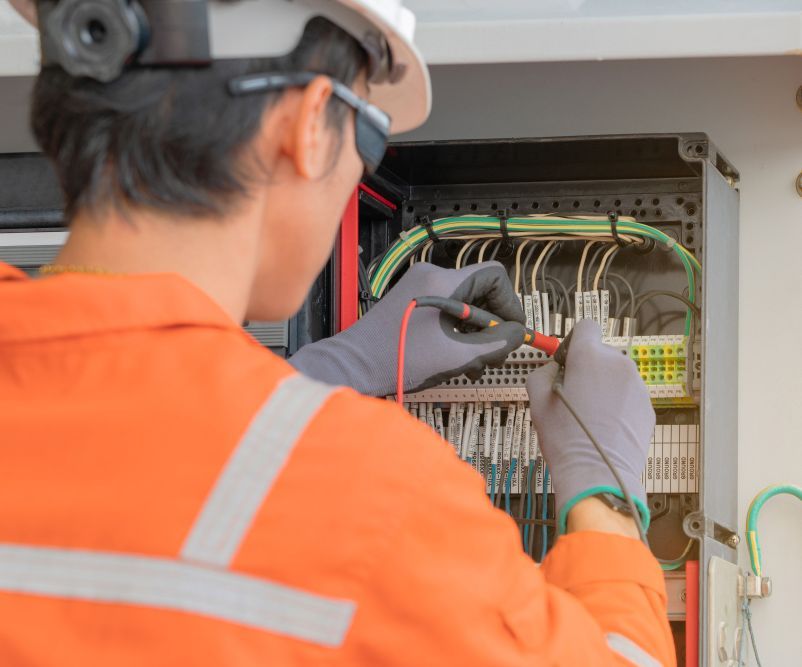 An Electrician Is Working On A Electrical Box With A Multimeter — Steve Mason Electrical In Port Macquarie, NSW