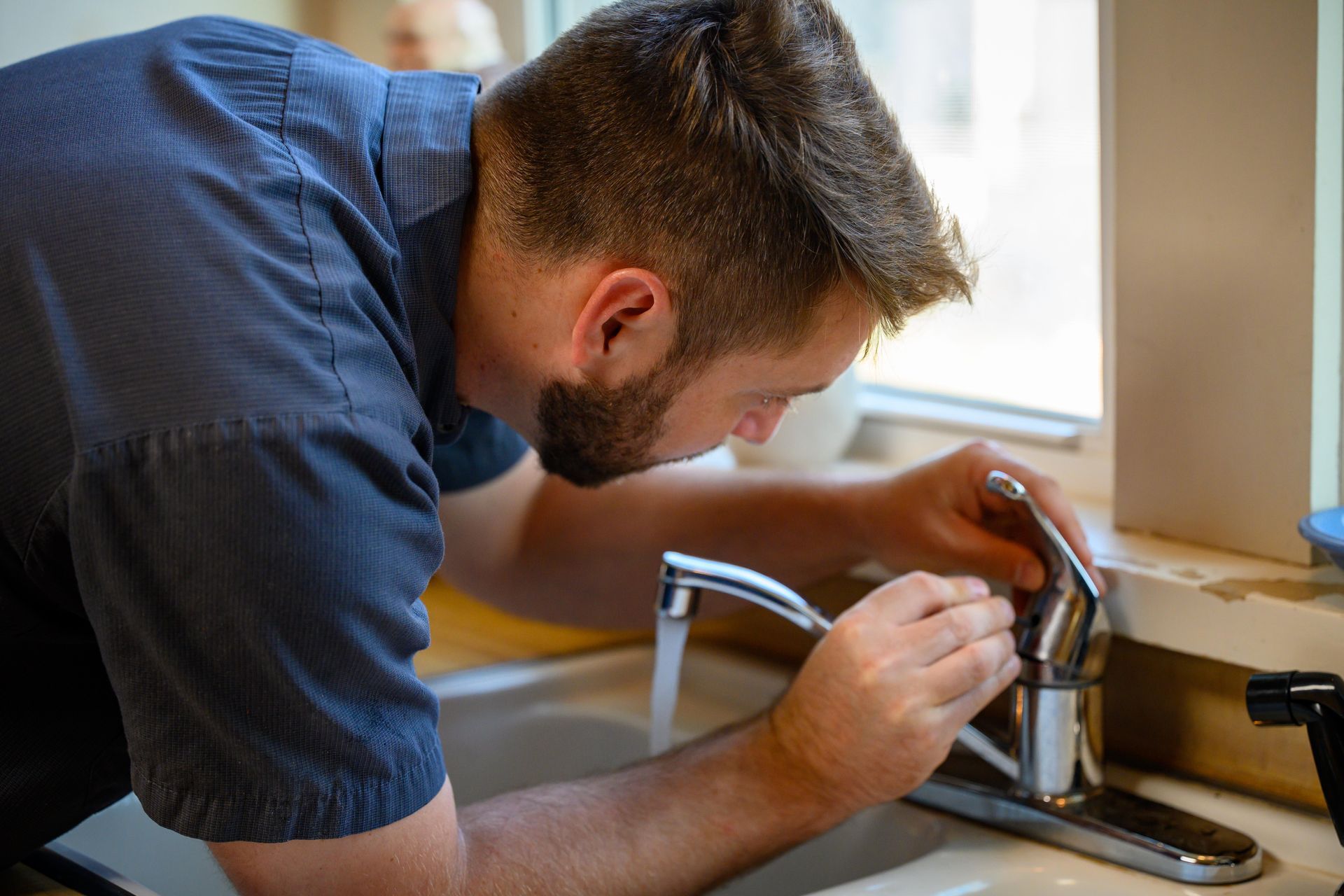 A man and a woman are washing dishes in a kitchen.