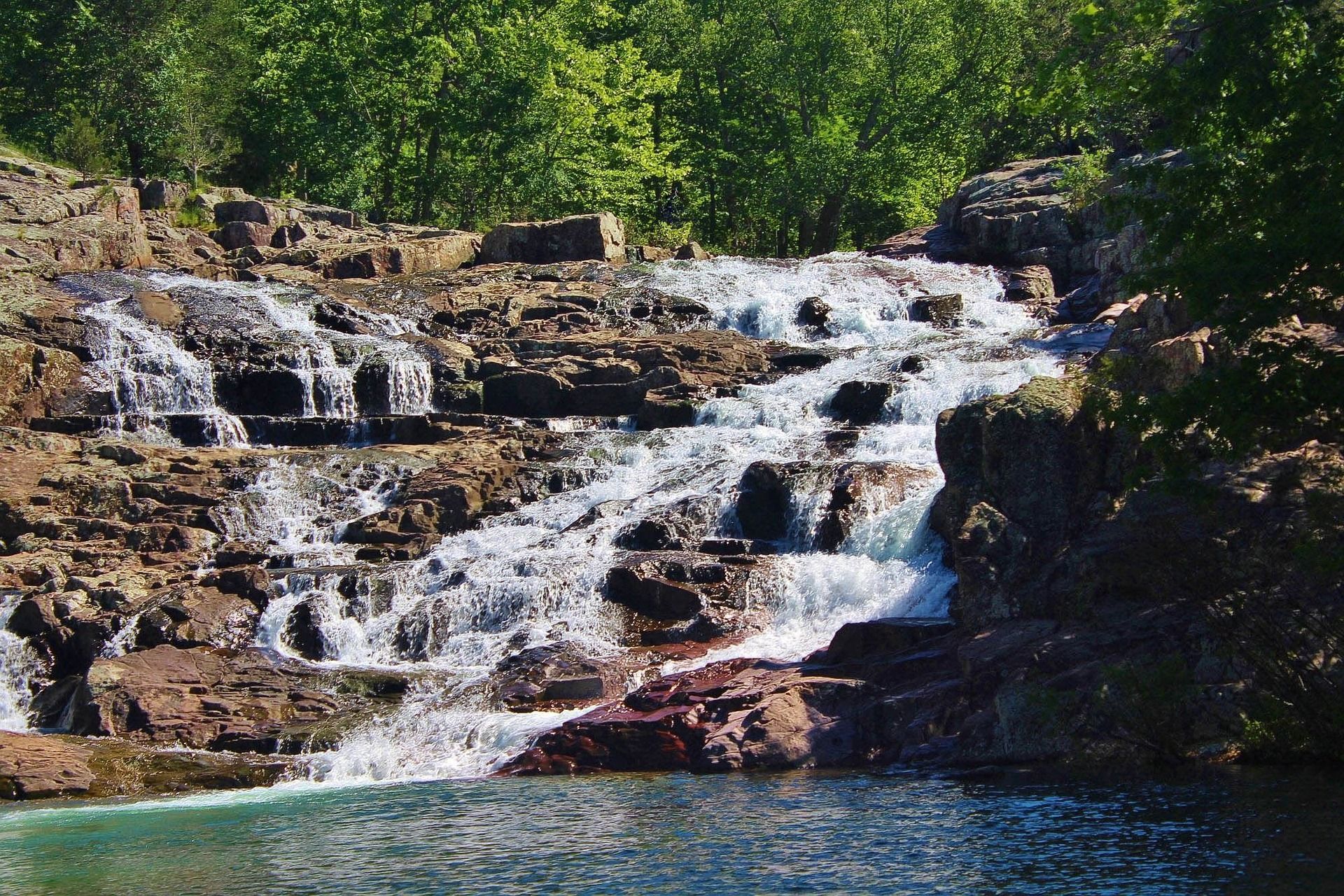 A waterfall is surrounded by rocks and trees