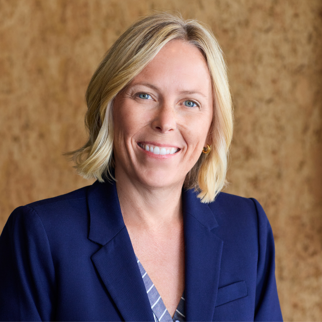 A woman in a blue jacket is smiling for the camera.