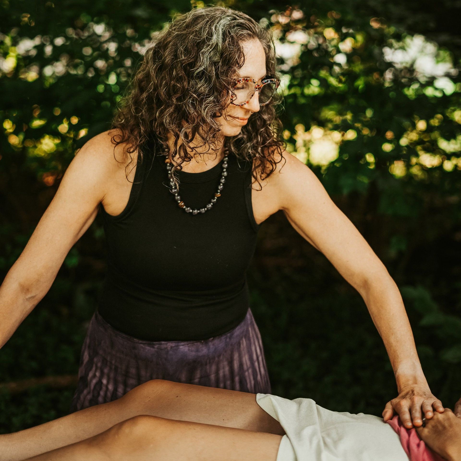 Woman in black tank top with hands on person’s face, outdoors.