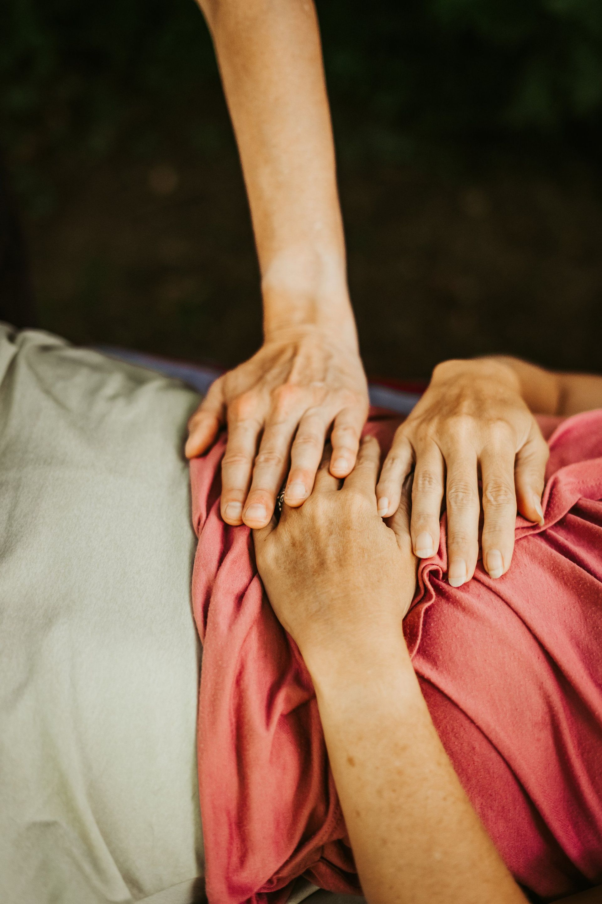 Two hands gently resting on another person's torso, suggesting care or healing.