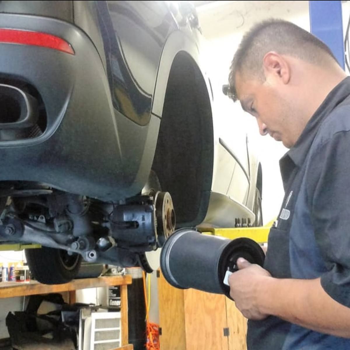 Mechanic inspecting a car's suspension component in a repair shop.