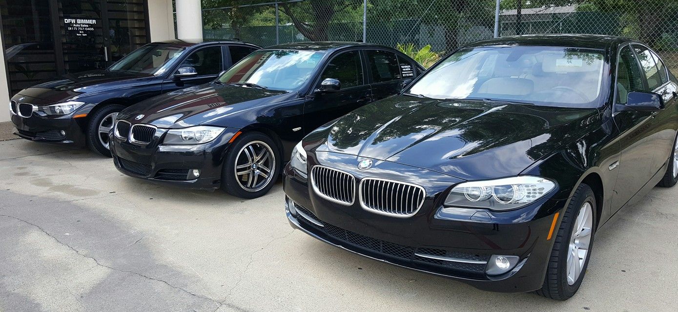 Four black BMW sedans parked outside.