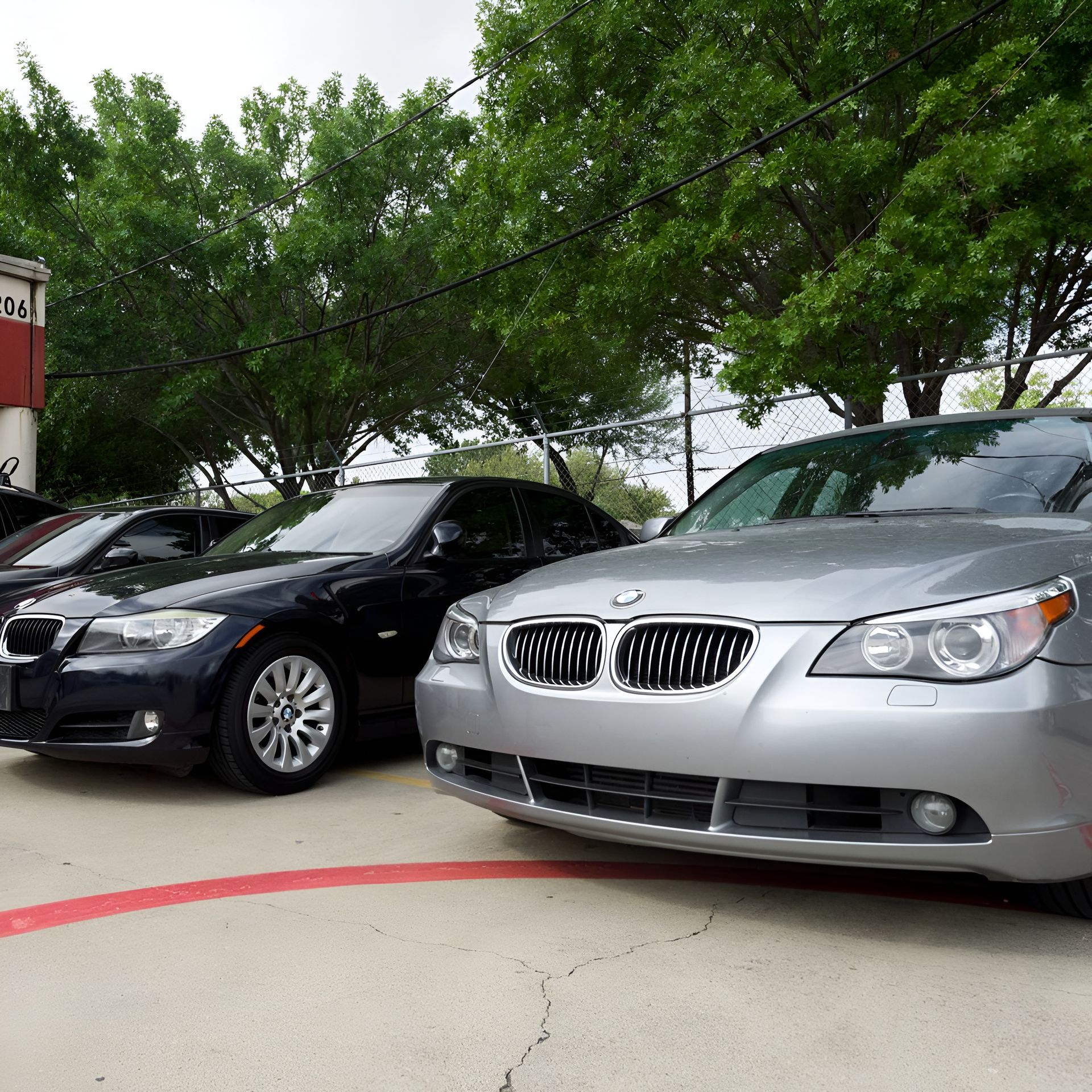 Three BMW sedans parked on a concrete lot; a silver one is closest to the camera.