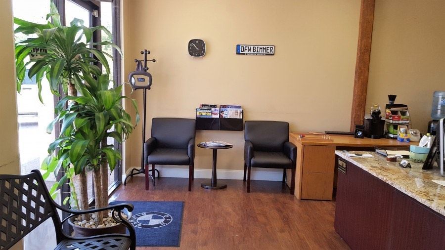 Reception area with waiting chairs, plant, desk, and door.