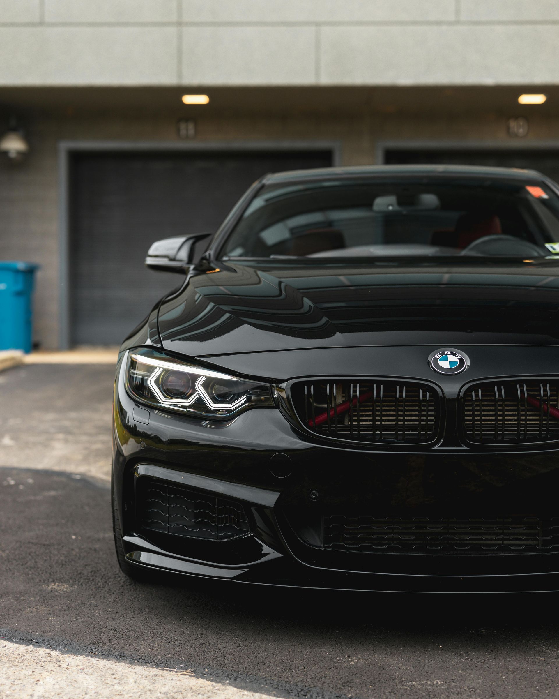 Black BMW sports car parked in front of a gray garage.