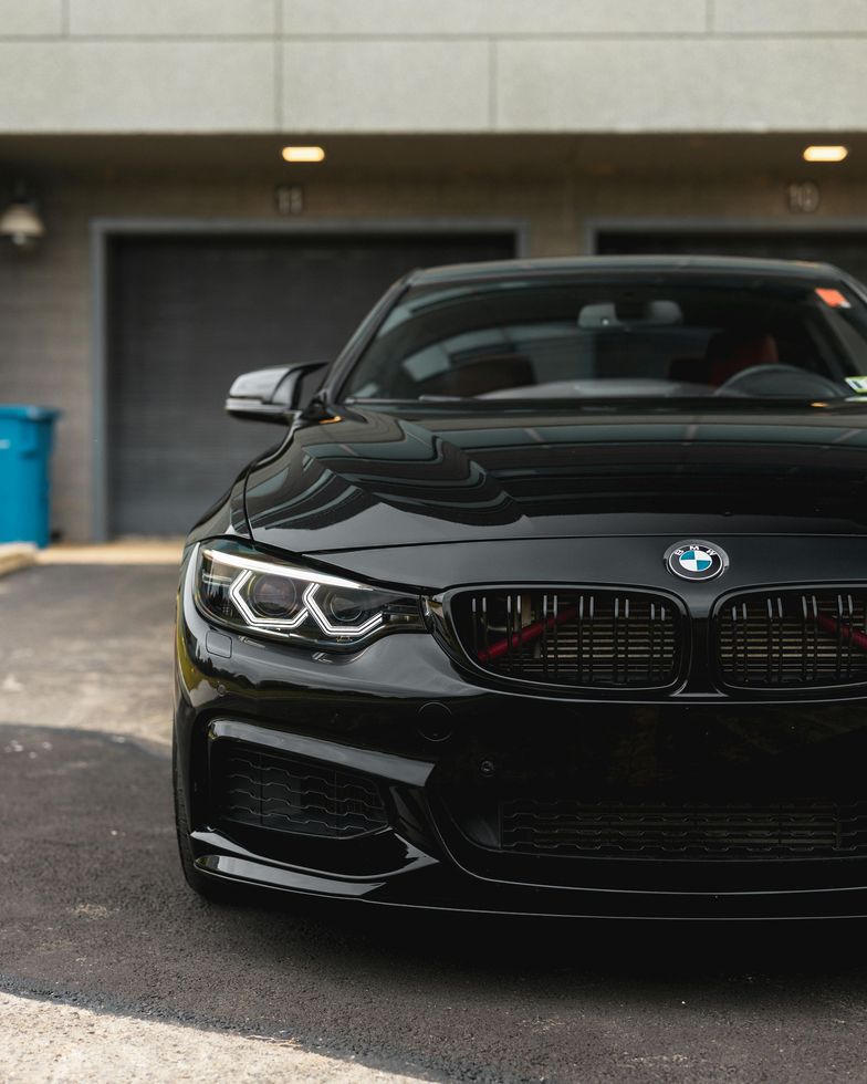 Black BMW sports car parked in front of a gray garage.