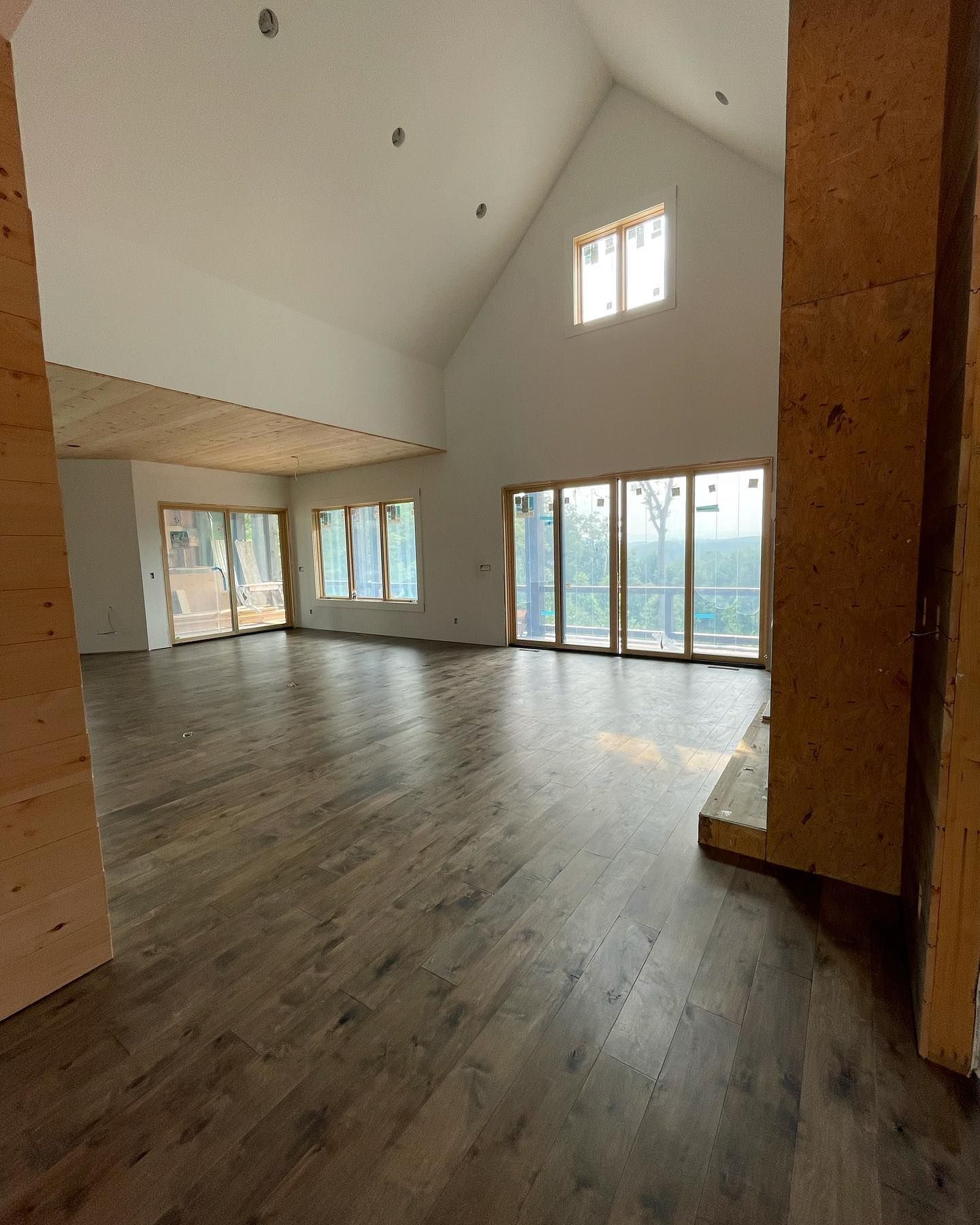 A large empty room with hardwood floors and lots of windows.