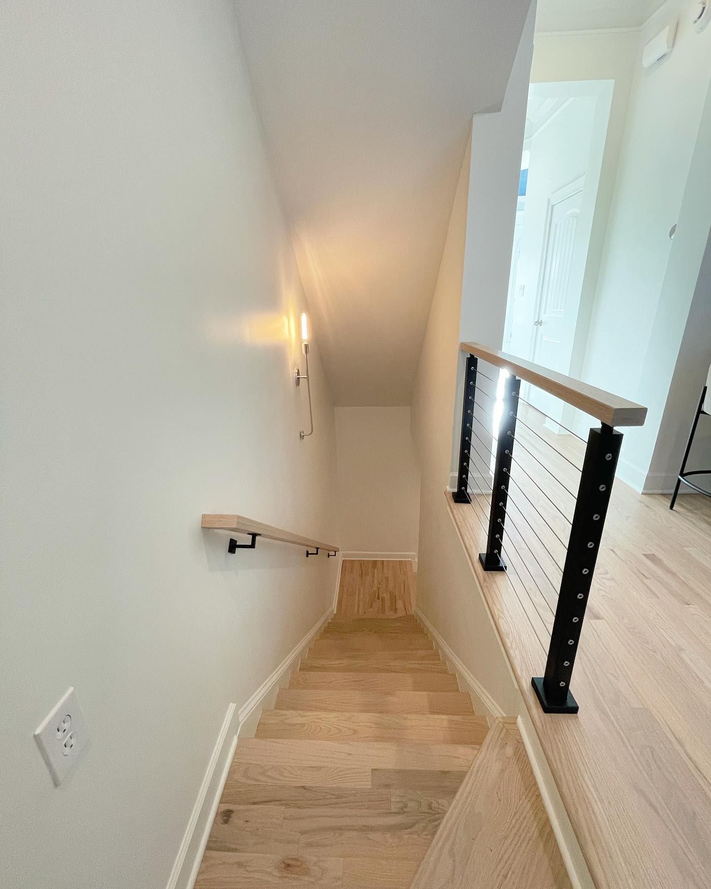 A wooden staircase with a black railing leading up to the second floor of a house.