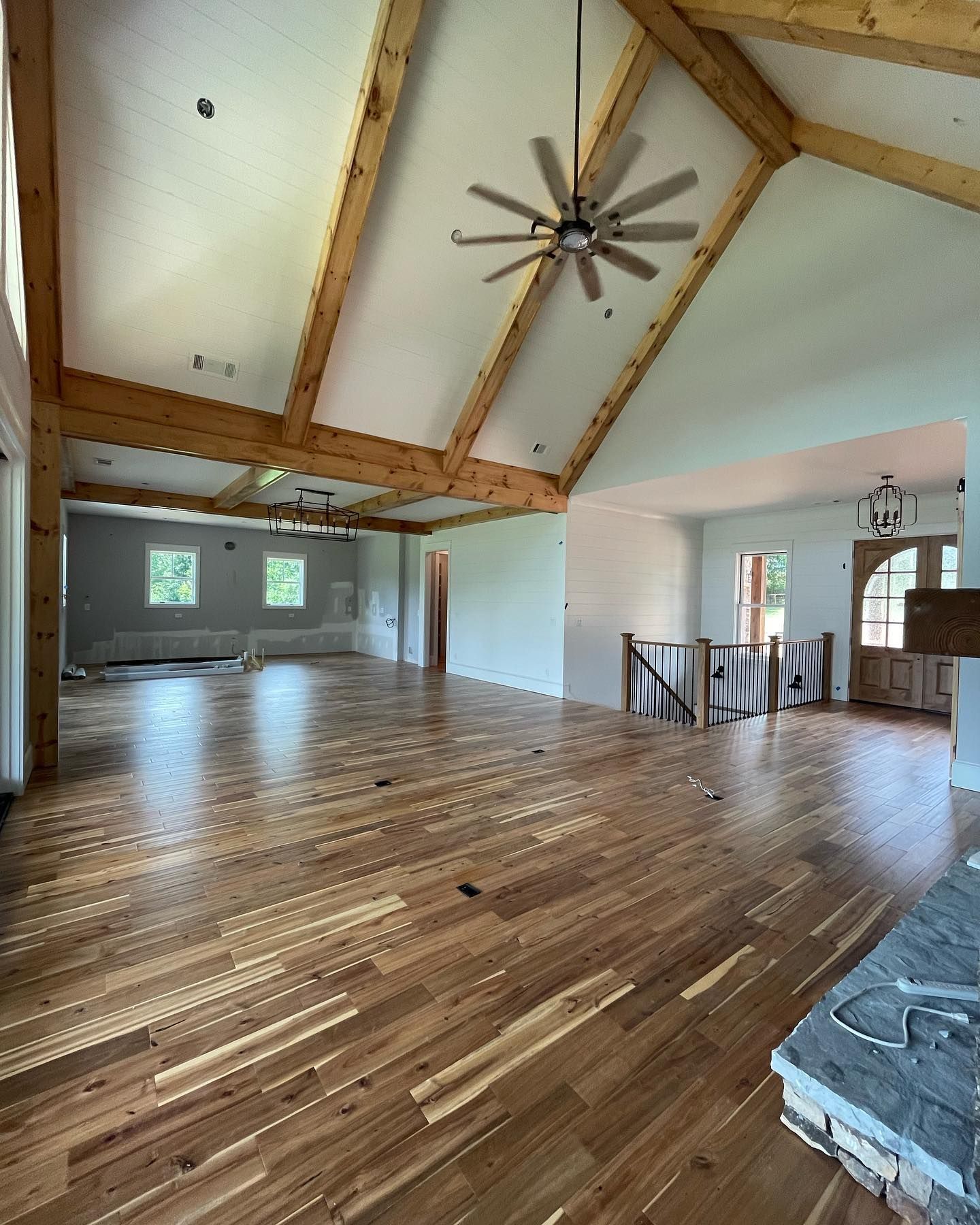A large empty room with hardwood floors and a ceiling fan.